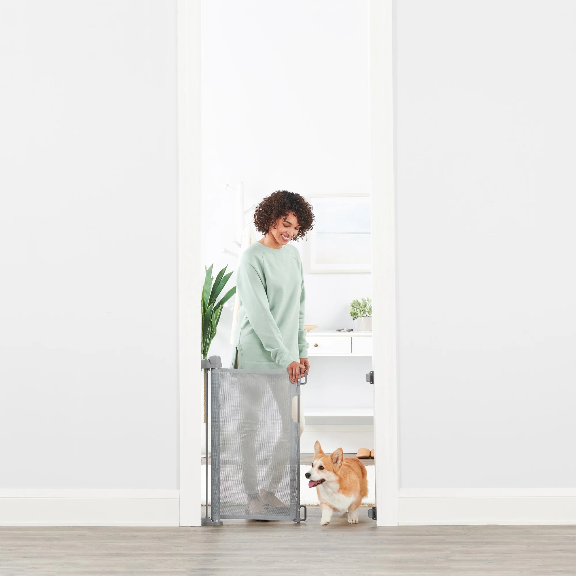 Woman opening Retractable Pet Gate for small dog.