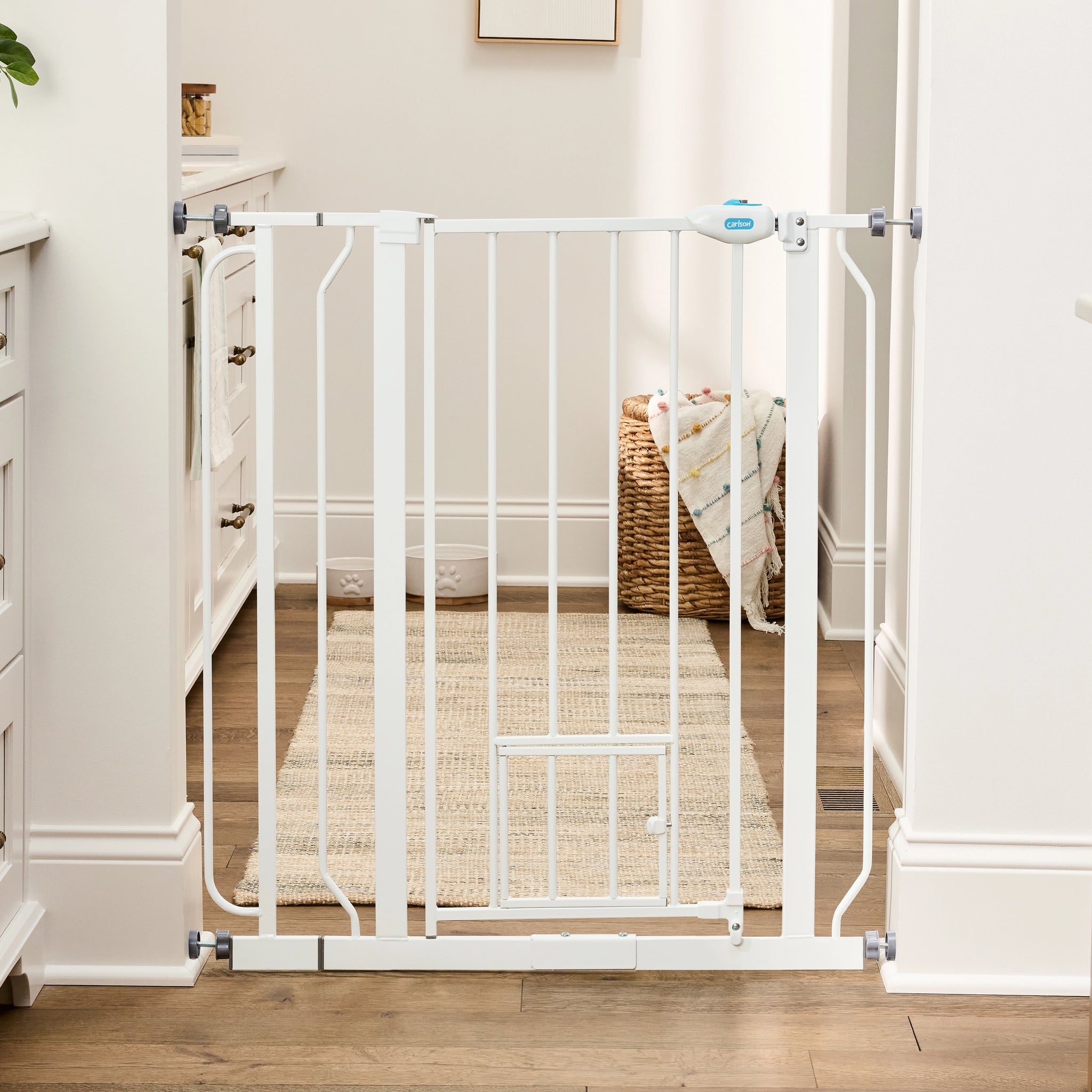 The Carlson 36” Extra Tall Walk-Thru Pet Gate with Small Pet Door in white, made of durable steel, is designed to keep pets safely contained. It features a 36” height, expandable width (29” to 36.5”), easy walk-through door, and a small pet door for small animals to pass through while keeping larger pets confined.