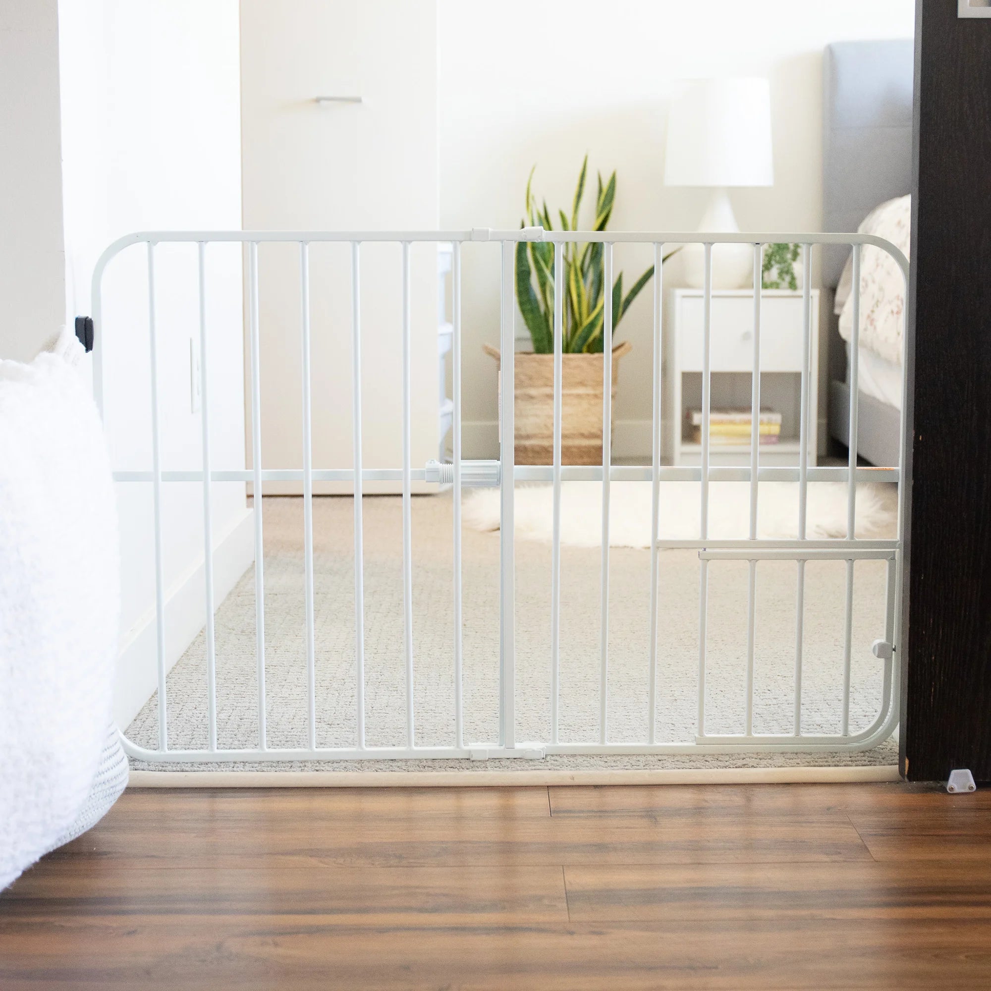 Carlson Tuffy® Expandable Pet Gate in white, durable steel frame, pressure-mounted, adjustable 26"-38", with small pet door for easy access.
