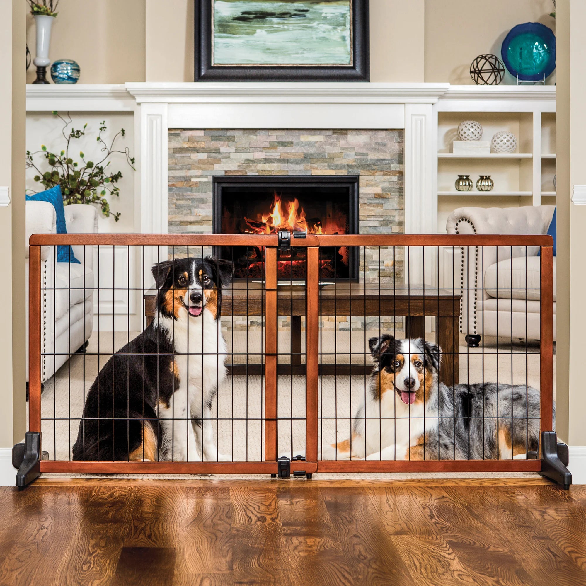 Two dogs sitting behind the Design Paw Extra Tall Extra Wide Freestanding Pet Gate while sitting in a living room.