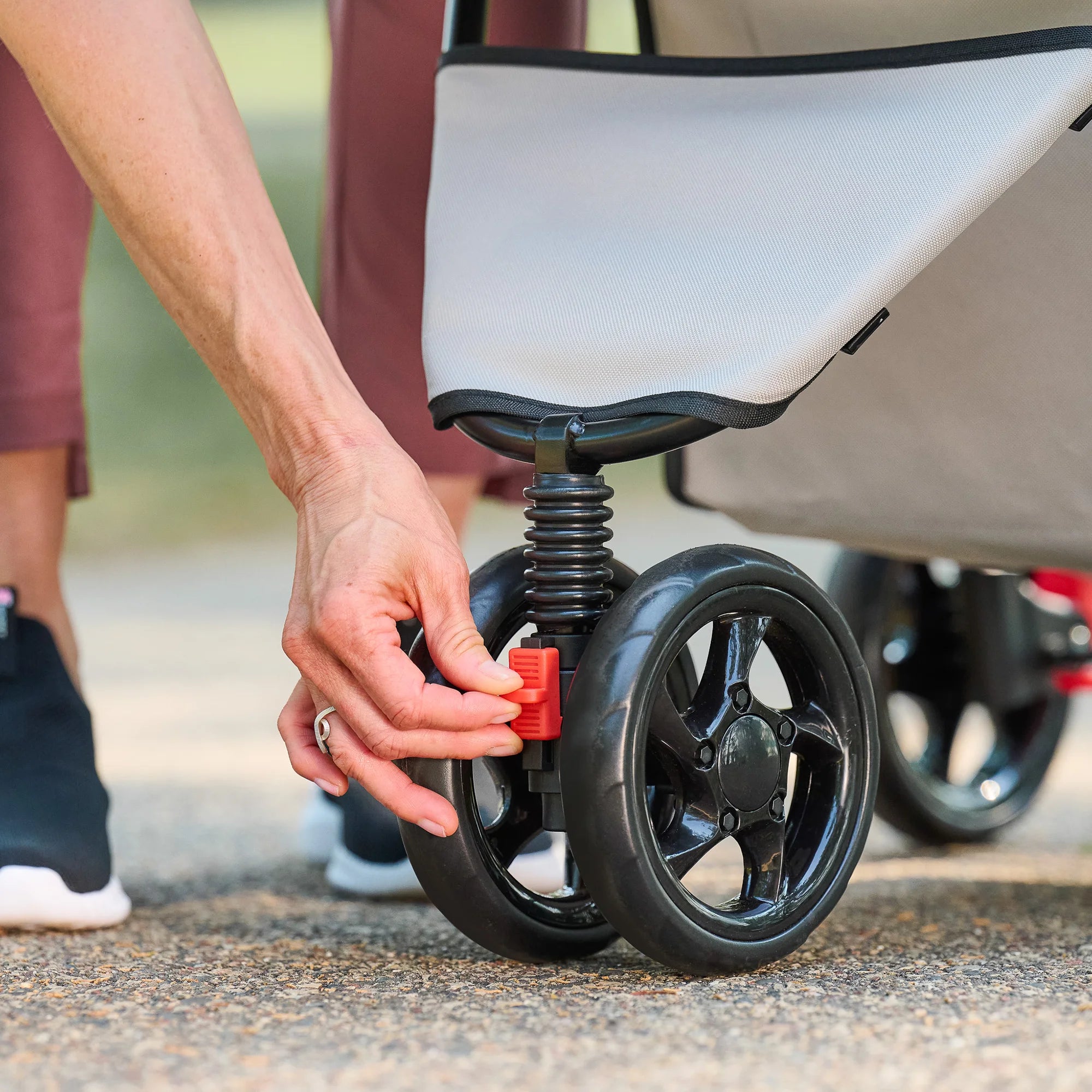 Woman locking front wheel hand on the Carlson Portable Pup Pet Stroller.