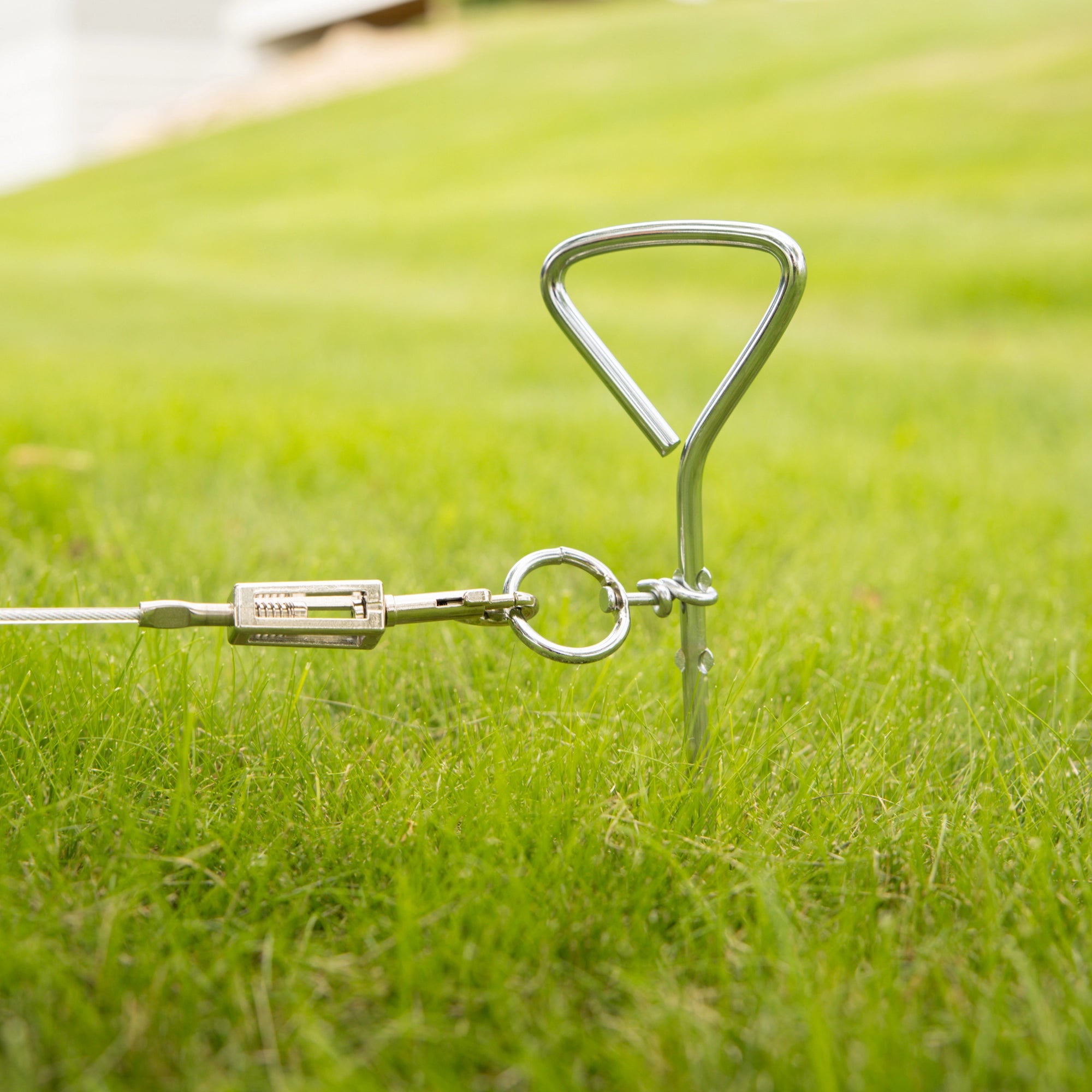 Carlson Triangle Screw Stake, a silver pet containment solution standing 18.3 inches tall. It features a triangle top and screw-shaped body designed to securely anchor the stake into the ground. Ideal for use with Carlson Dog Tie-Out Cables, providing safety for pets at home or while traveling.