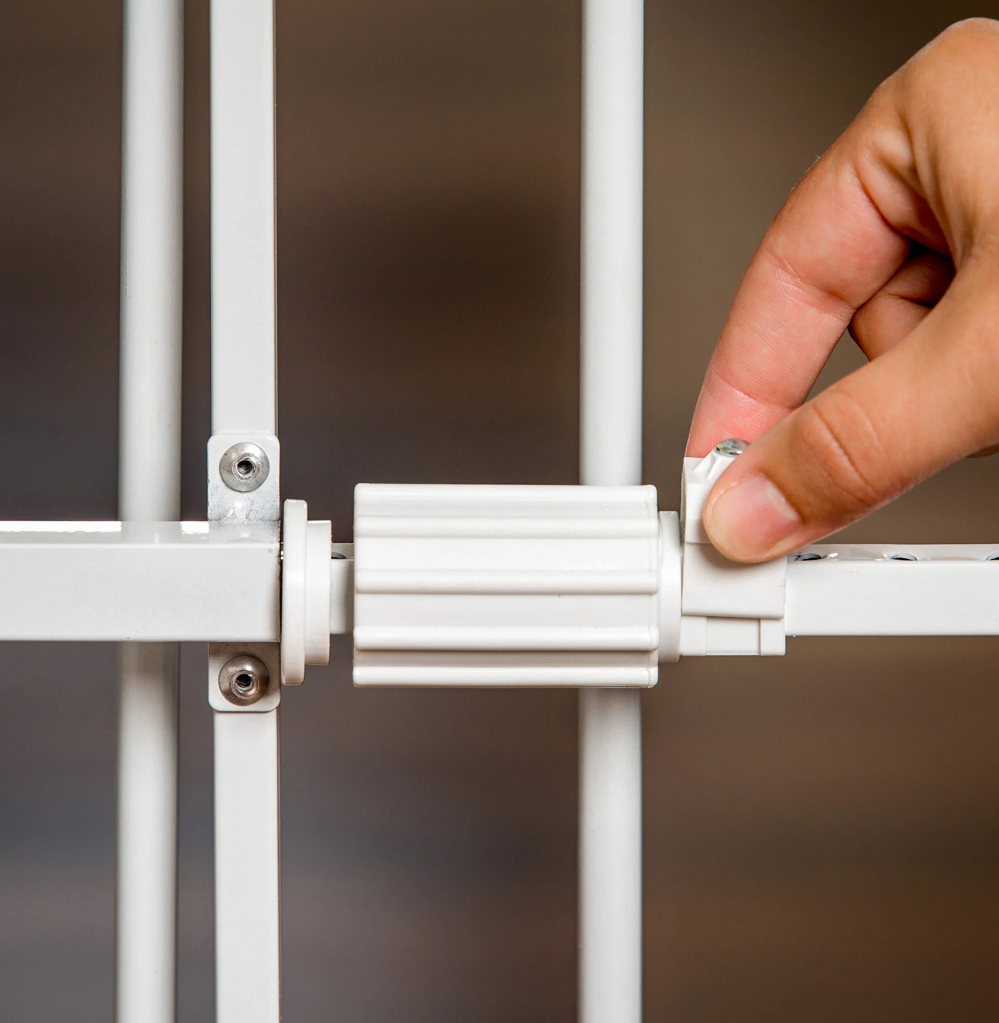 White Carlson Lil Tuffy® Expandable Pet Gate with small pet door, designed for small dogs and pets. The gate stands 18” tall and expands to fit openings between 22” to 38”. It features a sturdy all-metal frame and a pressure-mount system with rubber bumpers to protect walls.