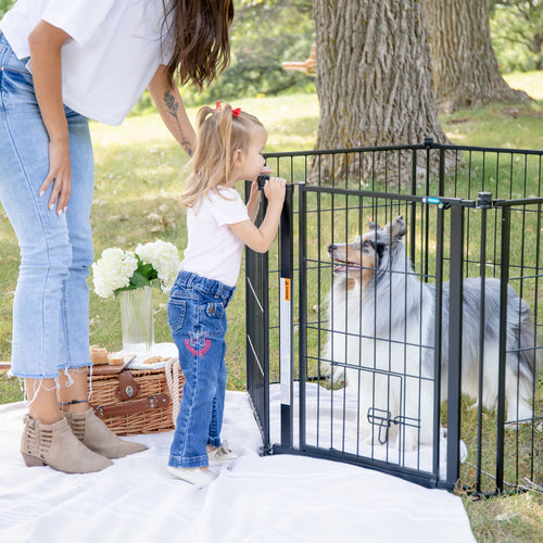 woman and little girl looking at dog in pet pen