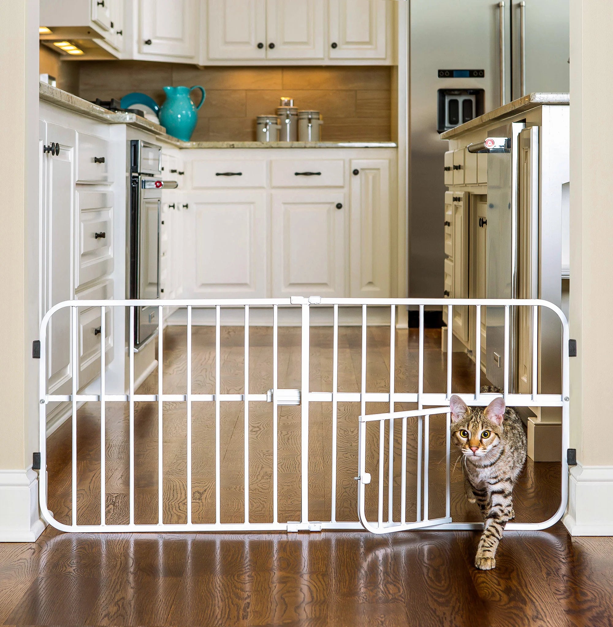 Cat walking through small pet door on Lil Tuffy® Pet Gate in kitchen.