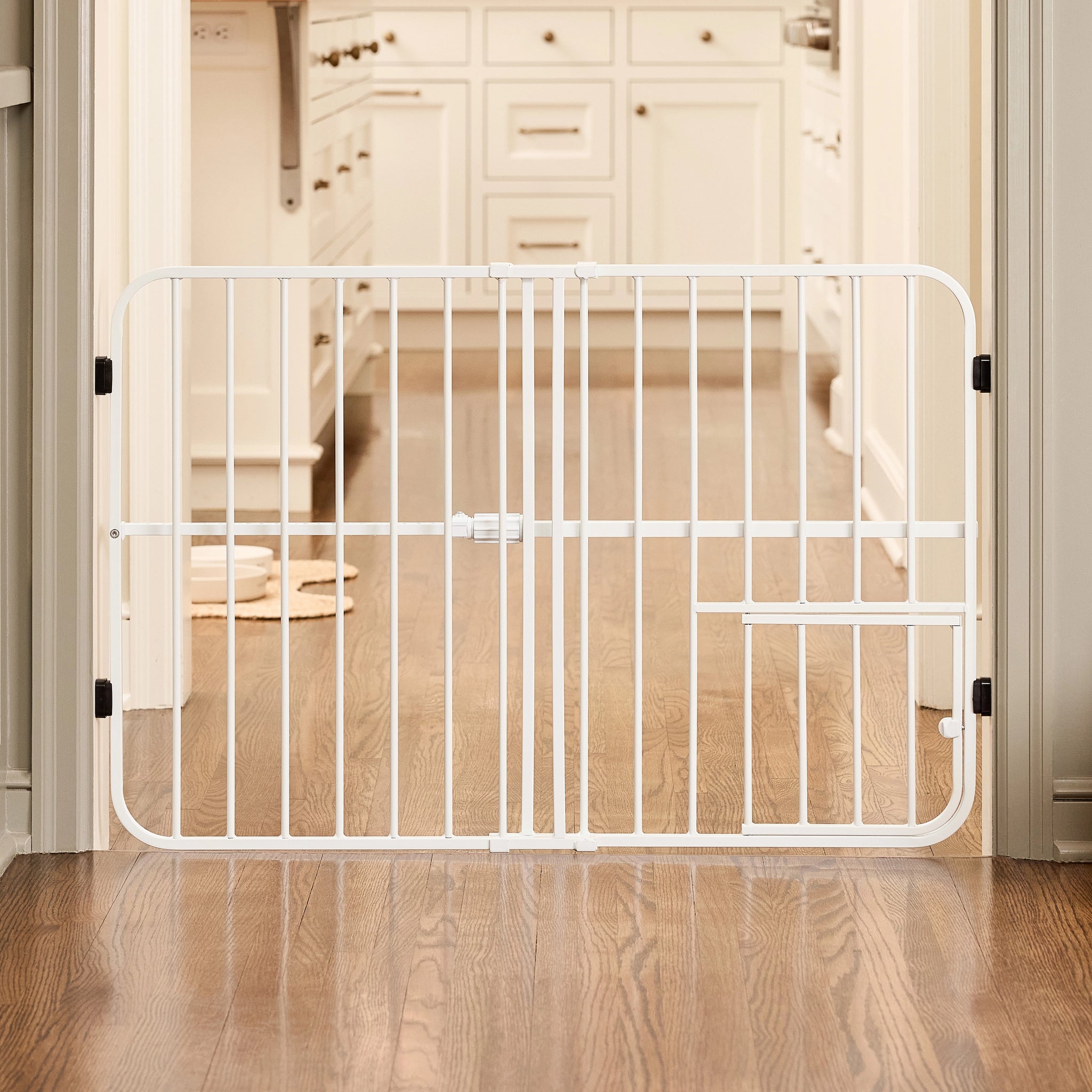 White metal gate in a home setting with wooden flooring and furniture.