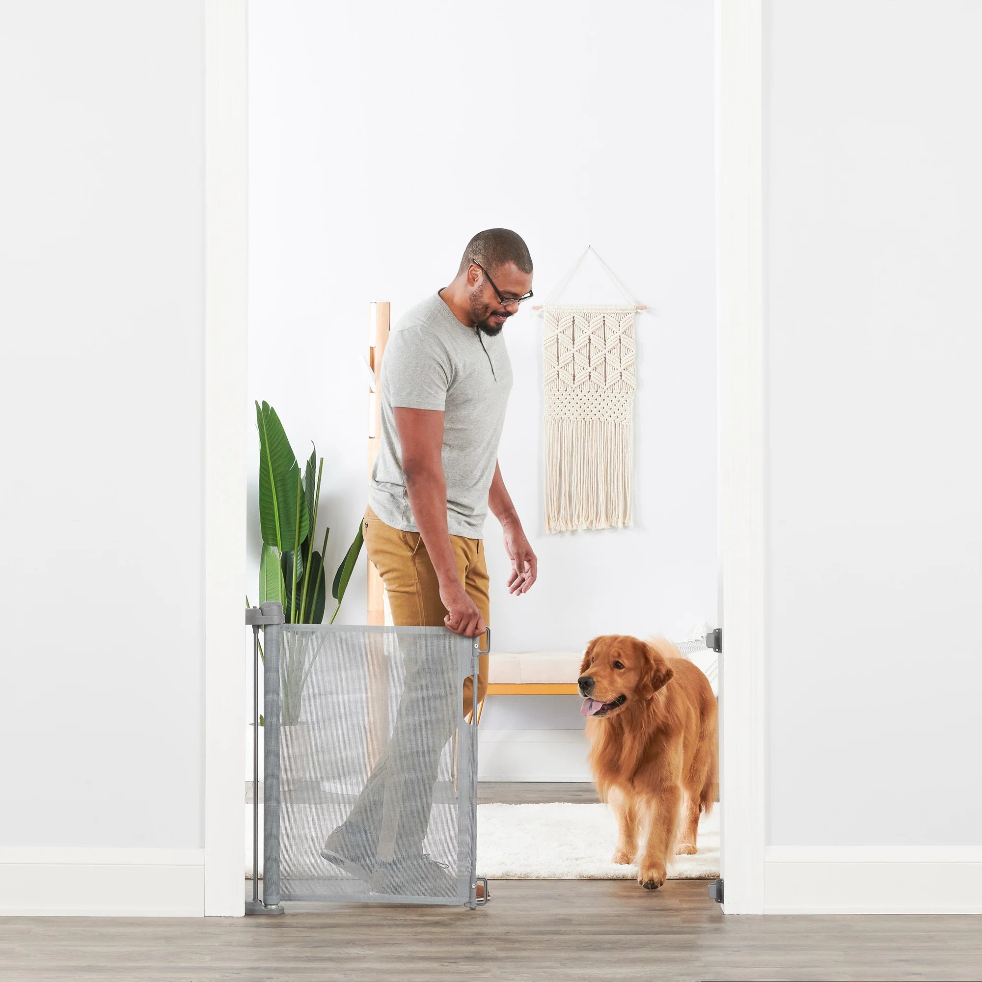 Man opening Retractable Pet Gate for dog.