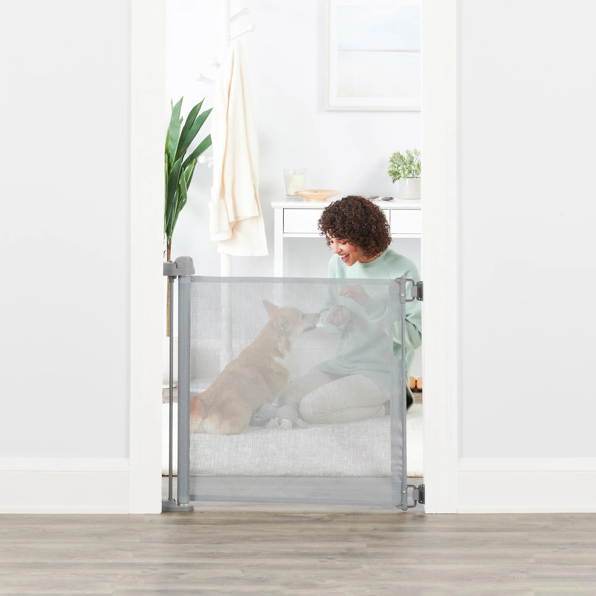 Woman playing with small dog behind Retractable Pet Gate.