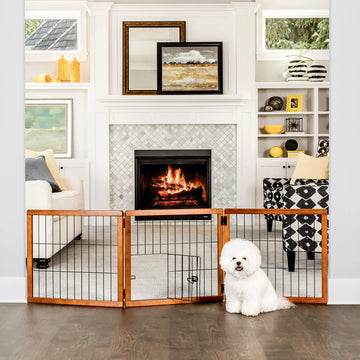Dog sitting in front of Design Paw 3 Panel Wooden Pet Gate in living room.