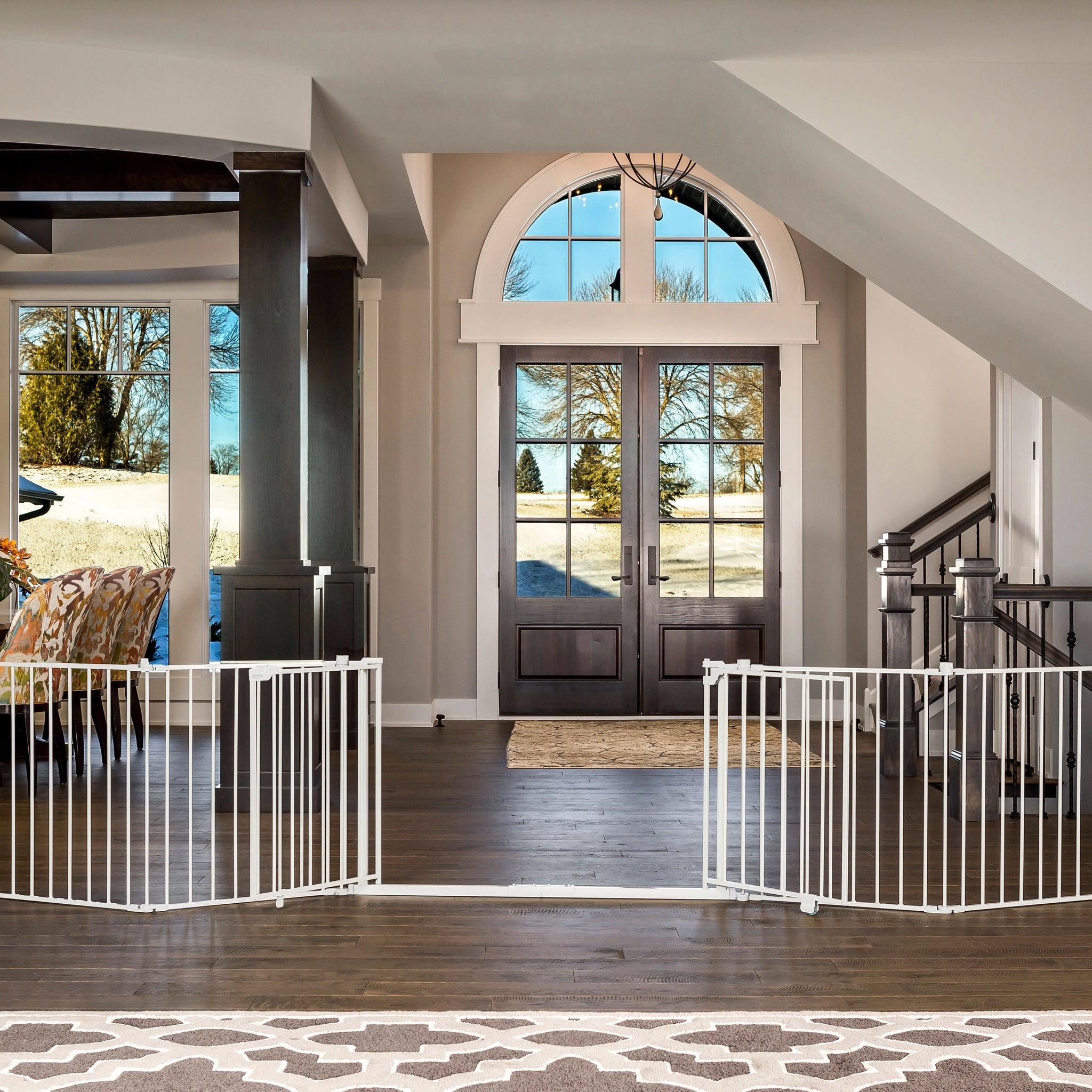 Foyer with large double doors, white baby gate, and staircase.