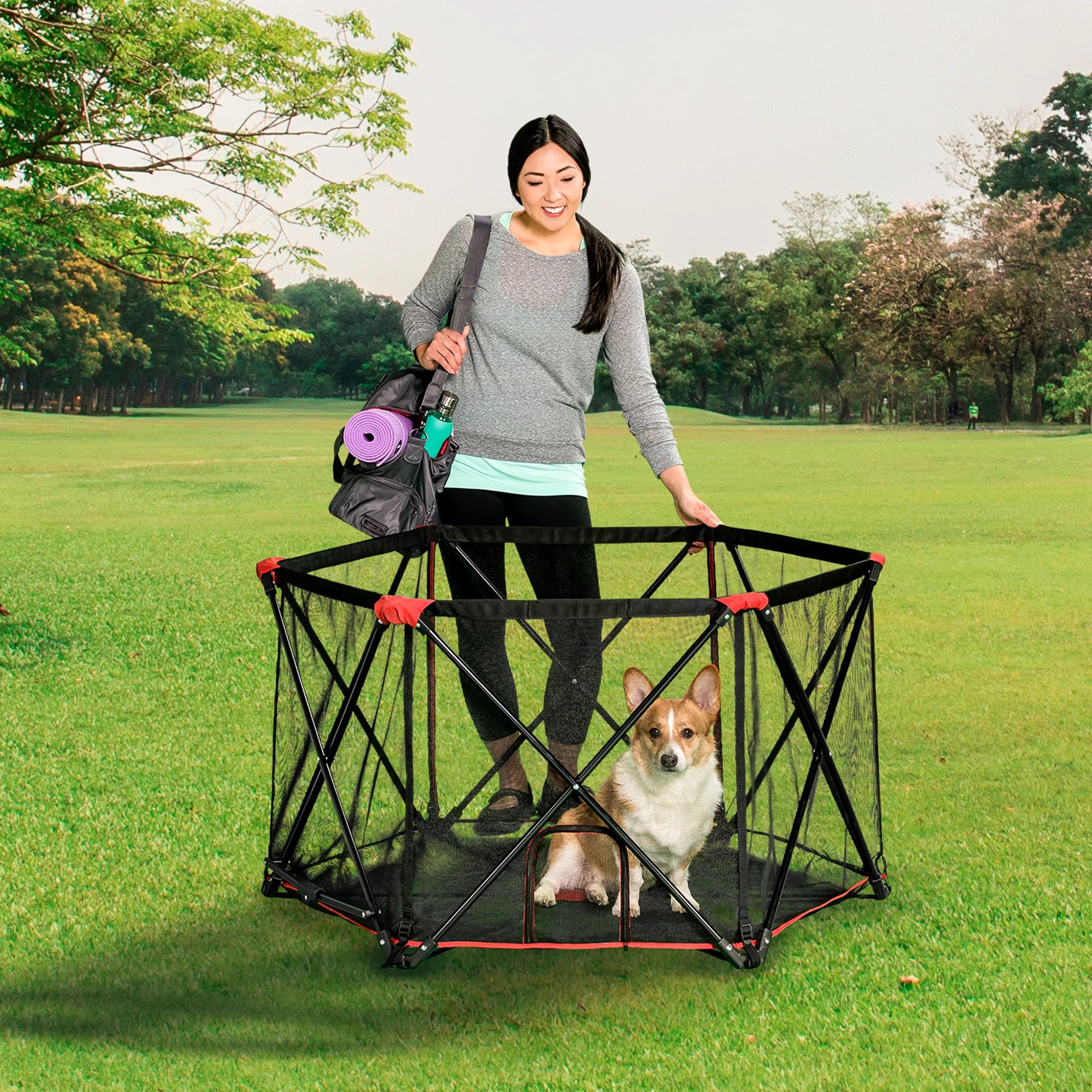 Woman at a park touching the Portable Pet Pen while looking down at her dog.