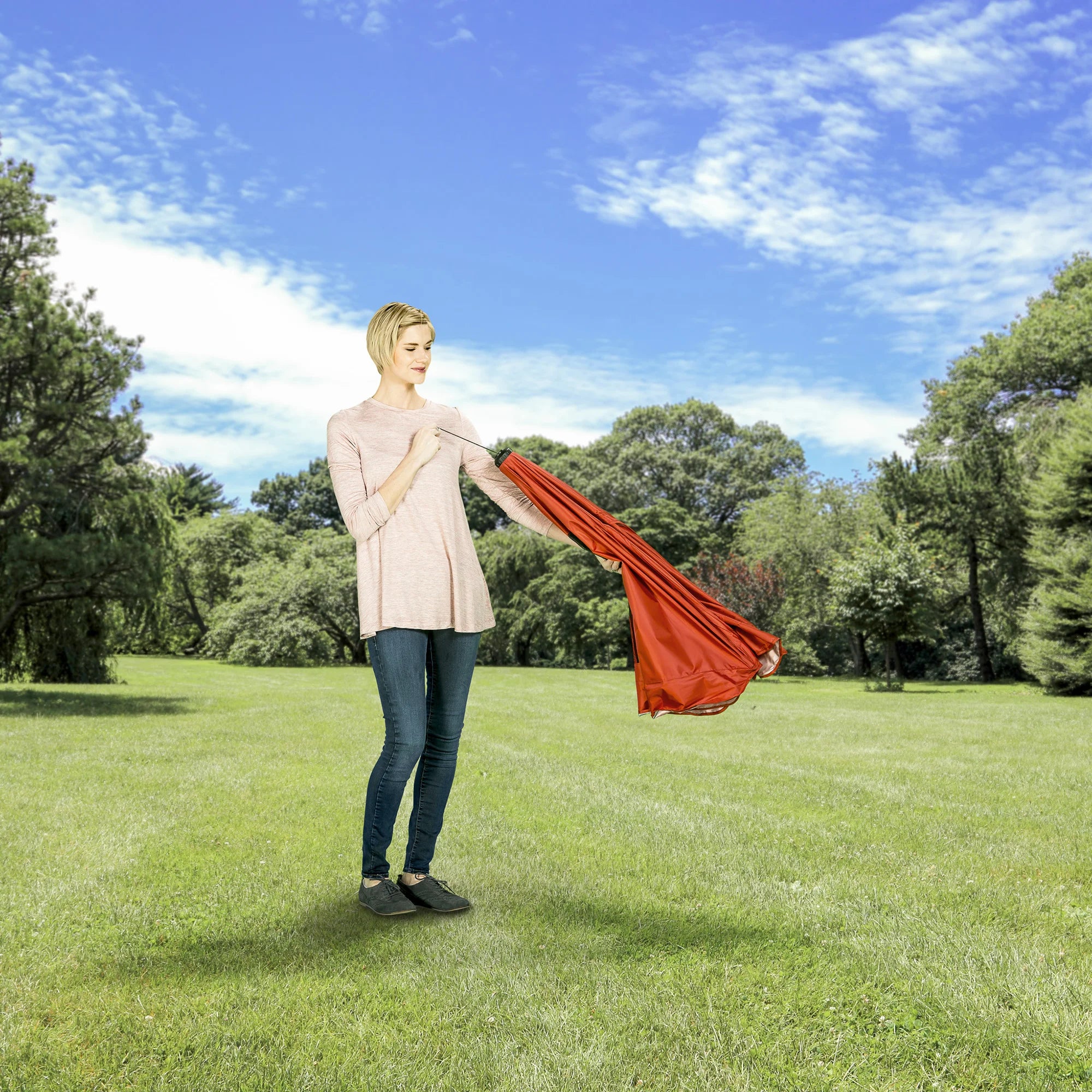 Woman folding the canopy of the Portable Pet Pen while at a park.