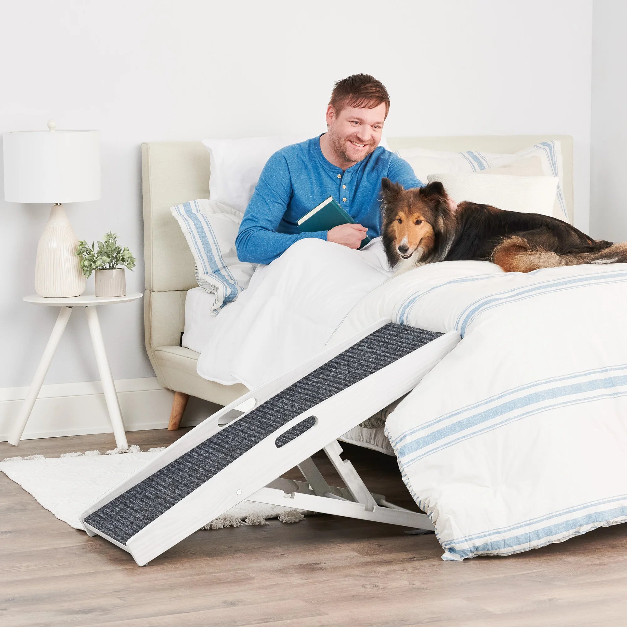 Dog on a bed next to a man with the Carlson Indoor Pet Ramp.