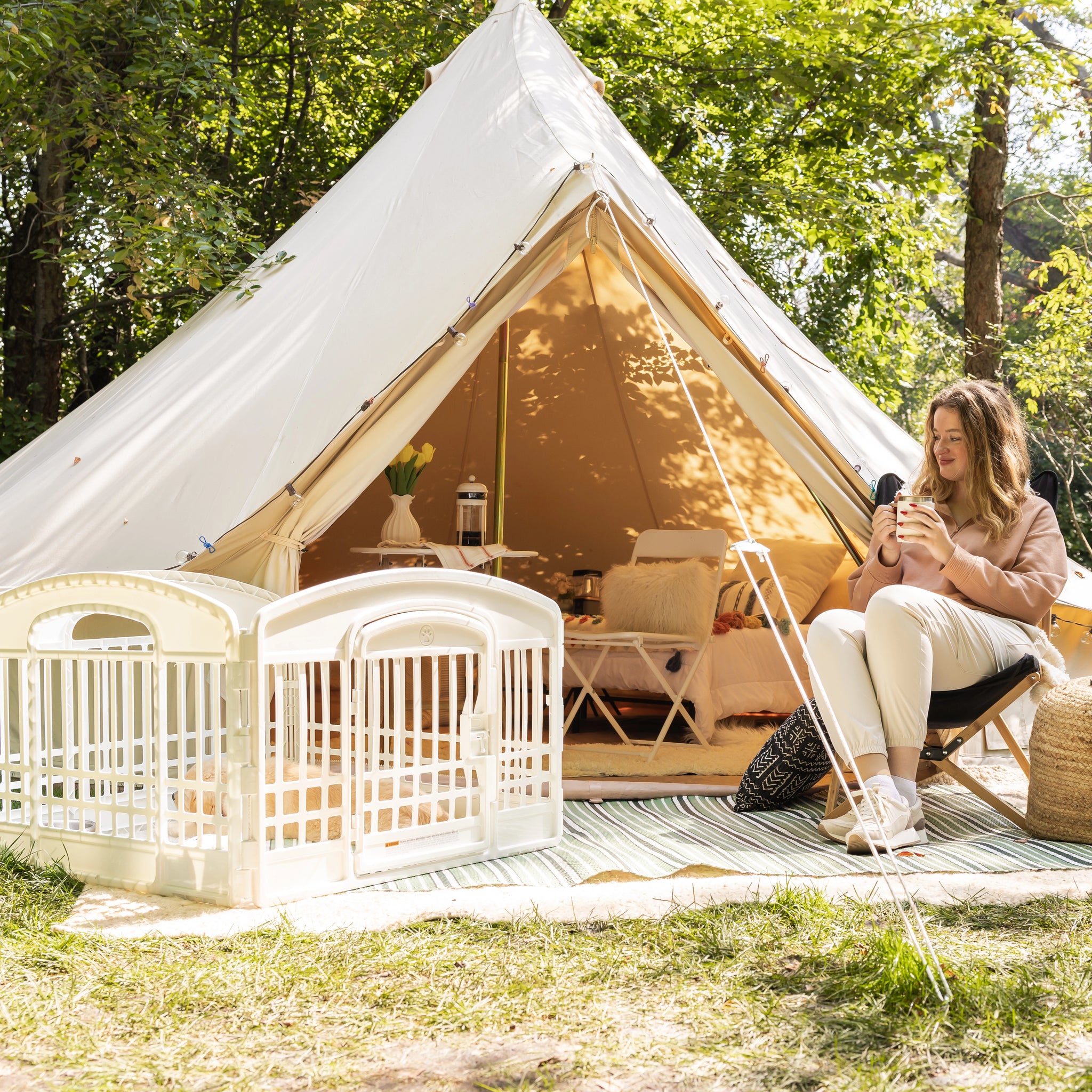 Woman sitting inside a large white tent in a forested area