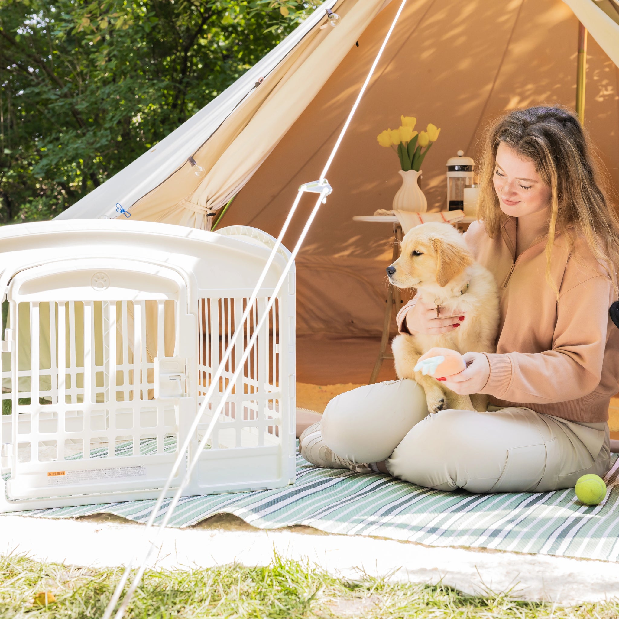 Woman with a dog sitting on a rug in front of a tent outdoors