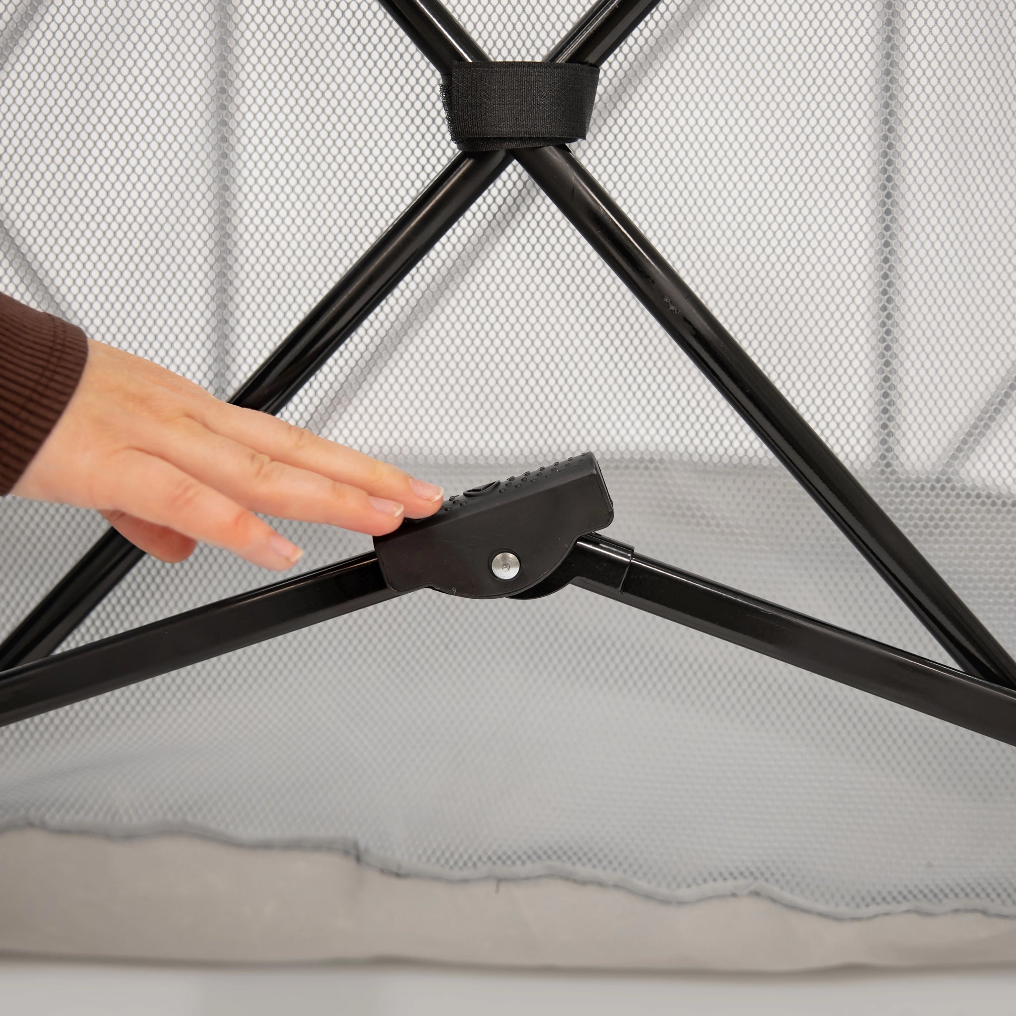 Person adjusting a black foot brake with a hand on a white background